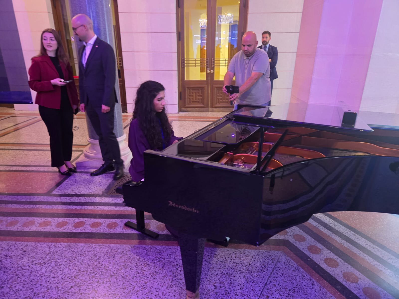 Sophia playing grand piano at a formal event